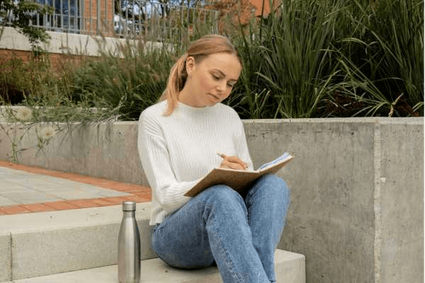 Woman sitting on steps writing in a journal